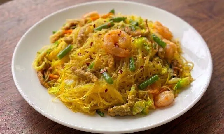 Singapore rice noodles with shrimp and green beans on a white plate